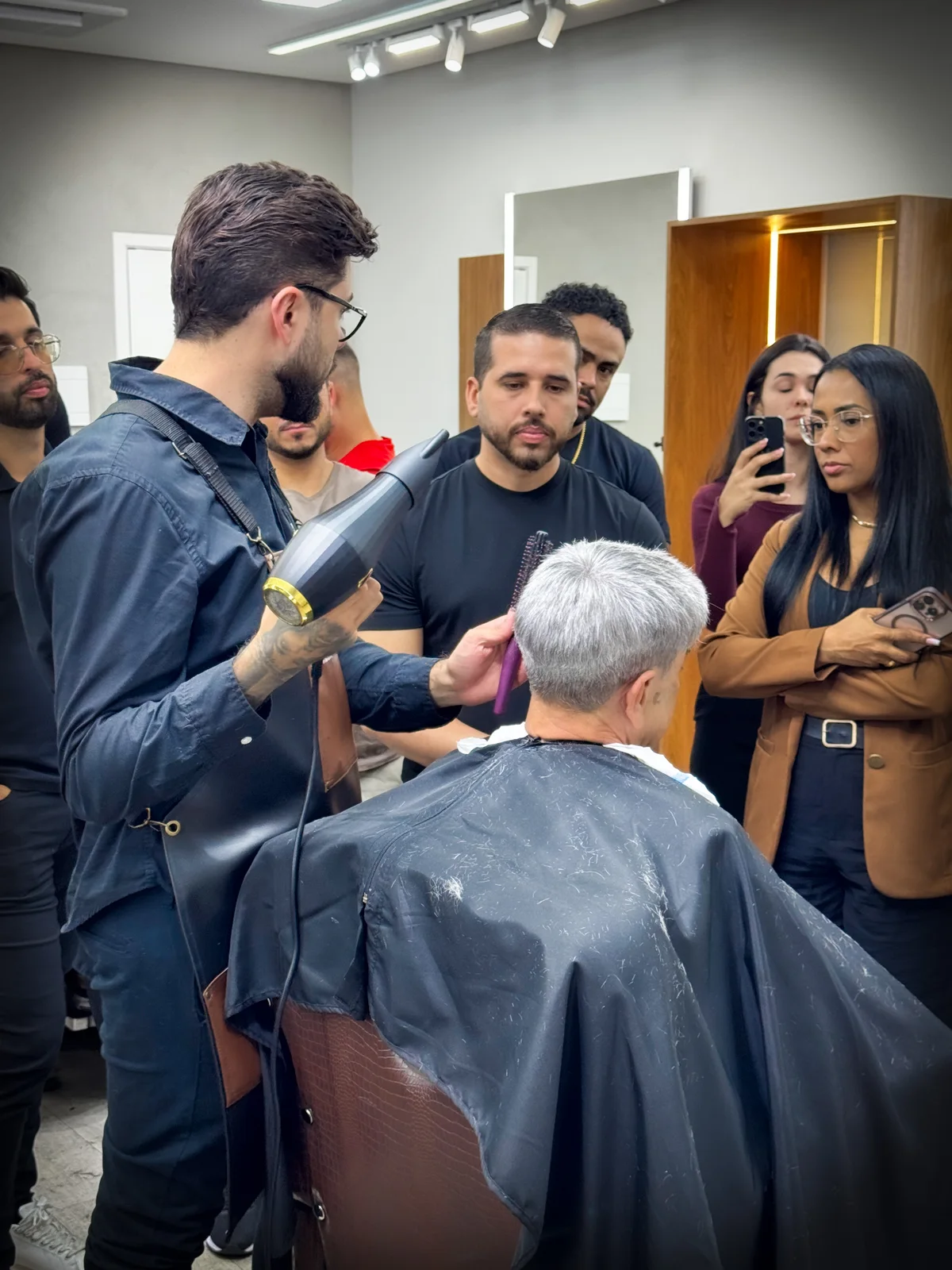 Francisco demonstrando uma técnica de cabelo enquanto a turma acompanha de perto